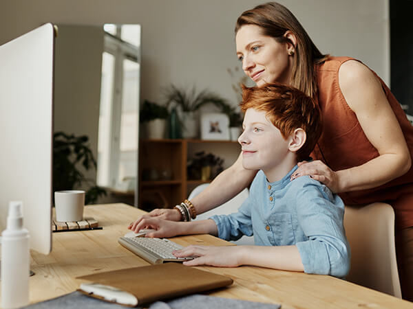 A photograph of a young boy and a woman using a desktop computer together - Chaos Theory | Serious Games Developer, Australia