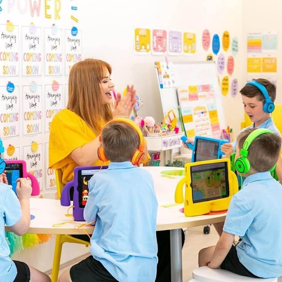 A photograph of students playing playEd on their iPads in class with their teacher